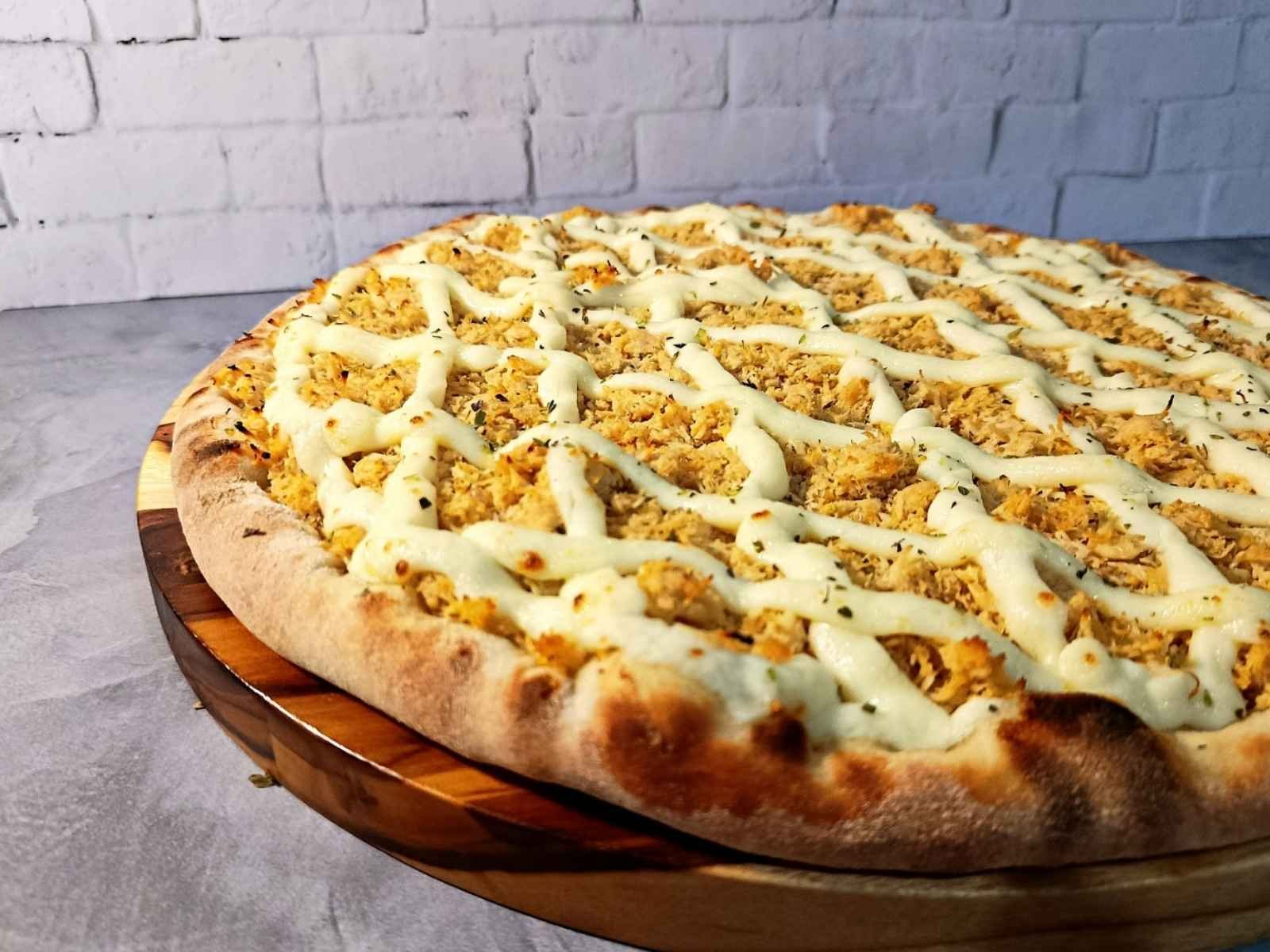 Pizza de Frango com Requeijão com borda dourada e recheio cremoso.